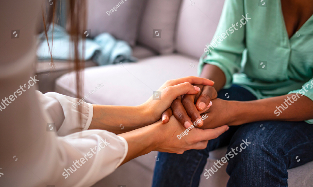 Two people holding hand while one comforts the other