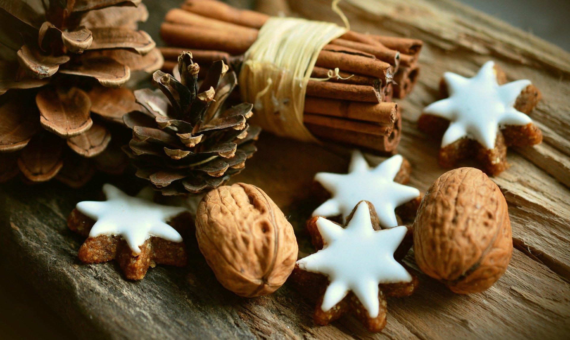 star-shaped cookies with icing, with decorative pines cones and cinnamon sticks