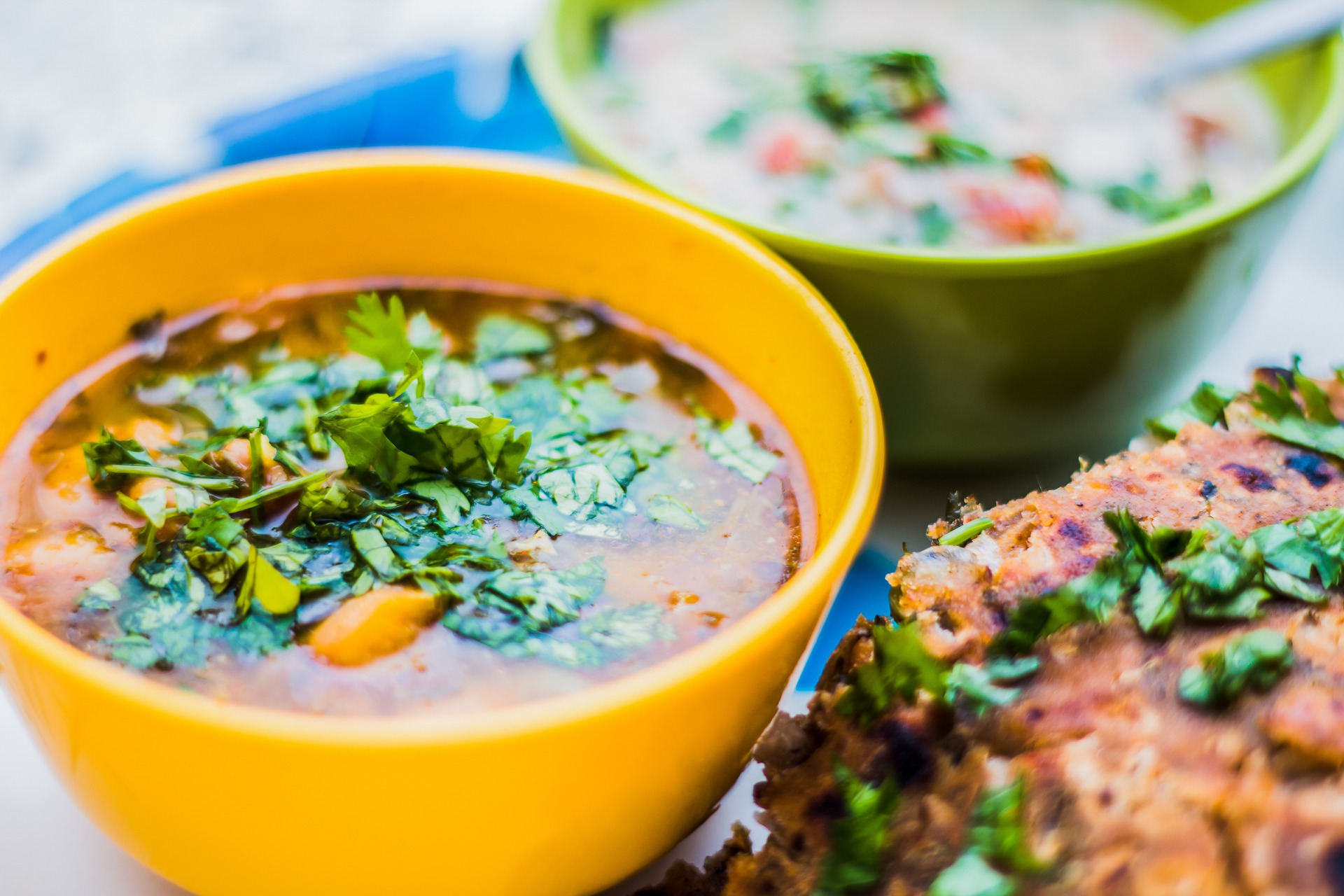 A close up of a rich and spicy beef broth garnished with fresh coriander.