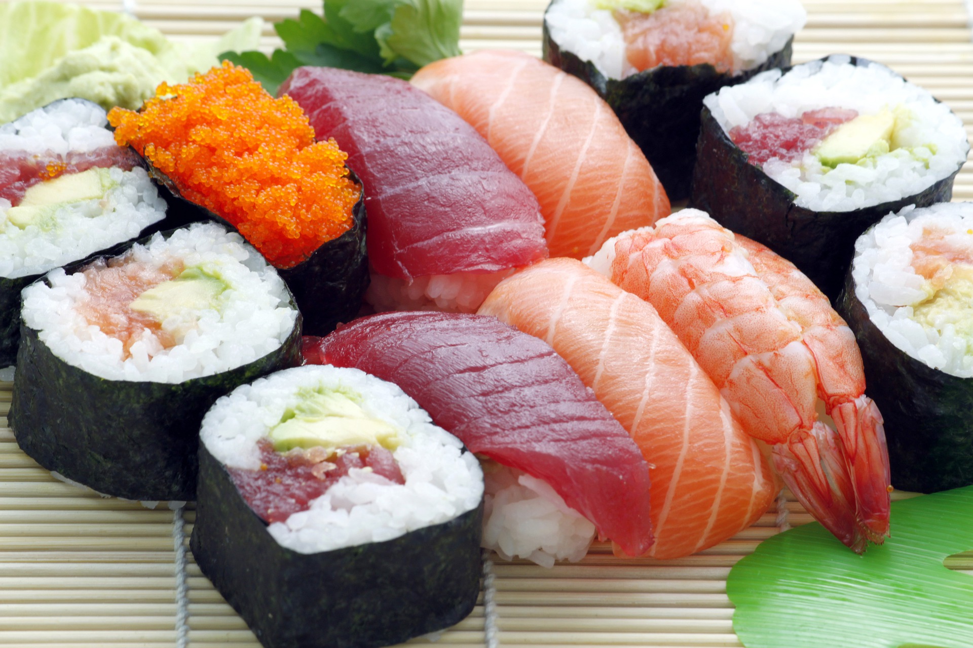 A geometric display of suchi composed of california maki rolls and tuna and salmon sashimi.