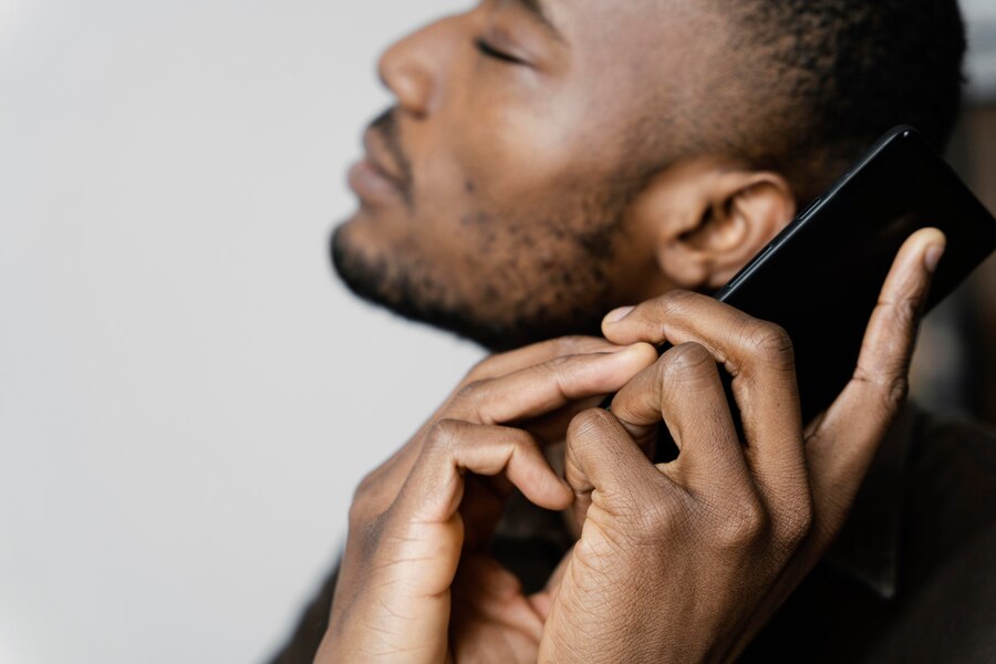 A man holds a smartphone by his ear with both hands, keeping one finger on
the screen